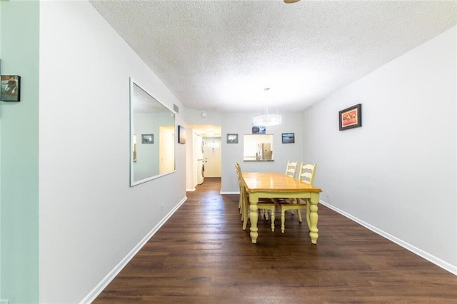 unfurnished dining area with dark wood-style floors, a textured ceiling, and baseboards