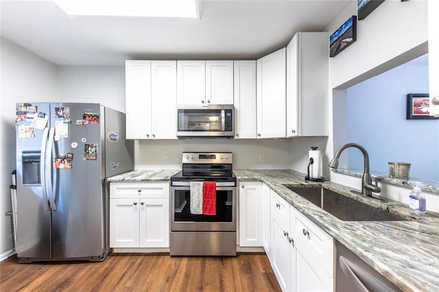 kitchen with appliances with stainless steel finishes, dark wood-style flooring, white cabinetry, and a sink