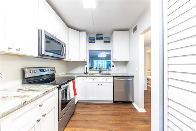 kitchen with stainless steel appliances, visible vents, dark wood-type flooring, white cabinets, and a sink