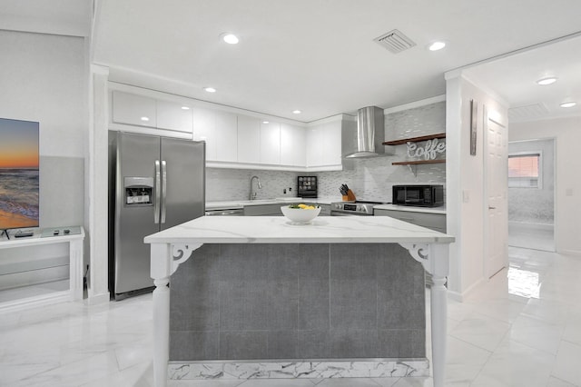 kitchen with light stone countertops, white cabinetry, a center island, wall chimney exhaust hood, and stainless steel appliances