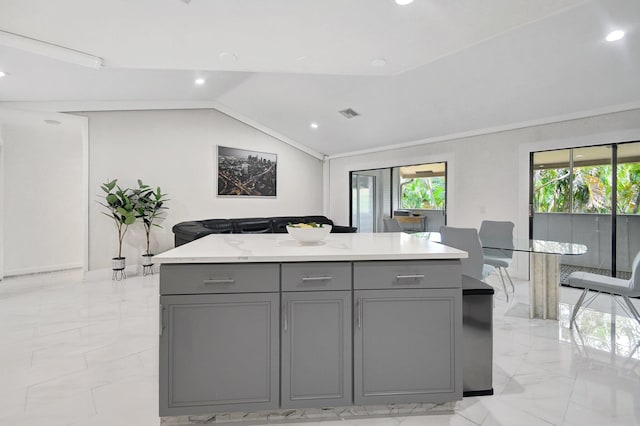 kitchen featuring gray cabinets, vaulted ceiling, a kitchen island, and light stone counters