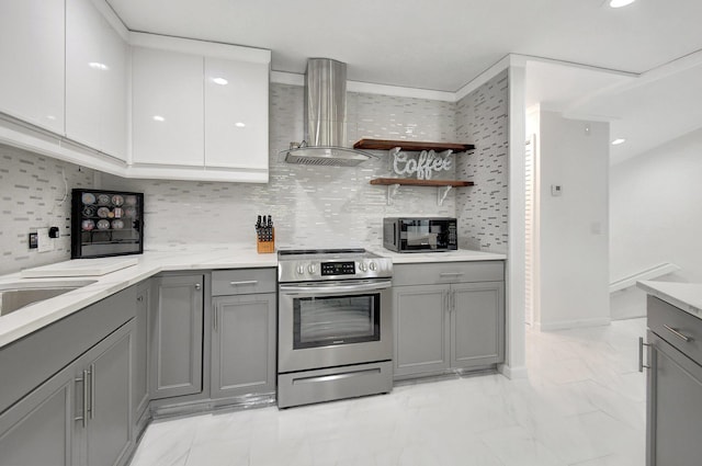 kitchen with wall chimney range hood, backsplash, stainless steel range with electric stovetop, gray cabinets, and white cabinets