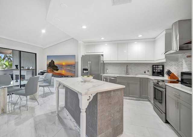 kitchen featuring sink, wall chimney exhaust hood, tasteful backsplash, a kitchen island, and stainless steel appliances