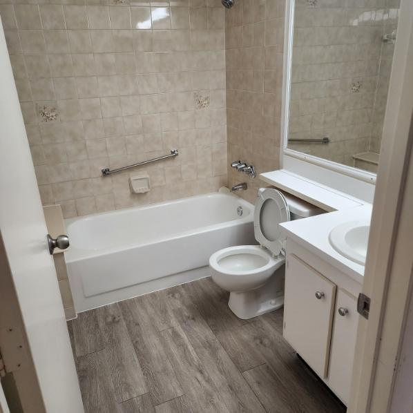 full bathroom featuring hardwood / wood-style floors, vanity, tiled shower / bath combo, and toilet