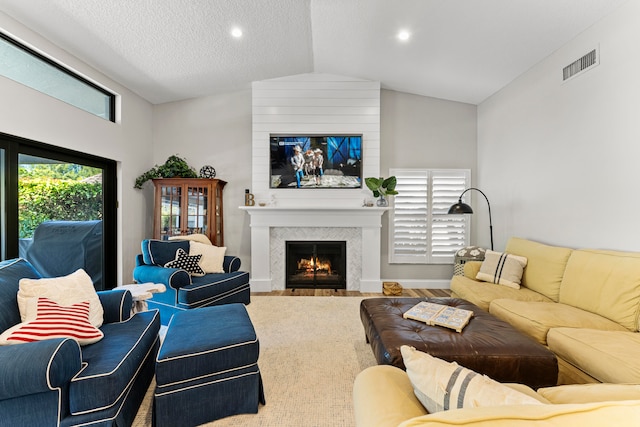 living room featuring ceiling fan, a fireplace, vaulted ceiling, and light hardwood / wood-style flooring