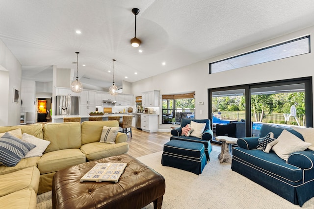 living room with a textured ceiling, a large fireplace, and lofted ceiling