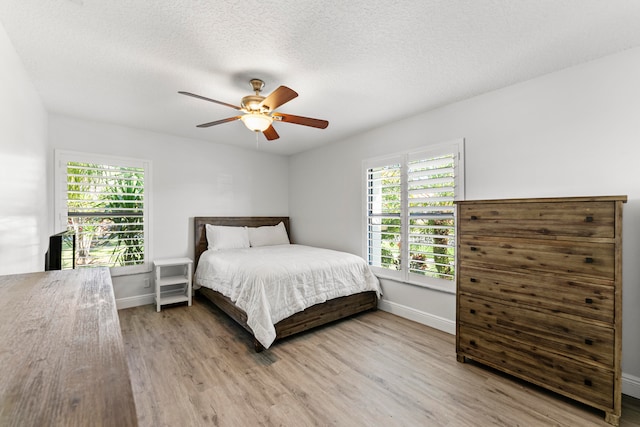 bedroom featuring hardwood / wood-style flooring, ceiling fan, and a textured ceiling