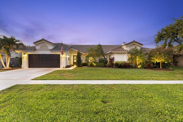 mediterranean / spanish-style home with a garage and a yard