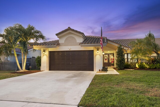 mediterranean / spanish-style home with a garage and a yard