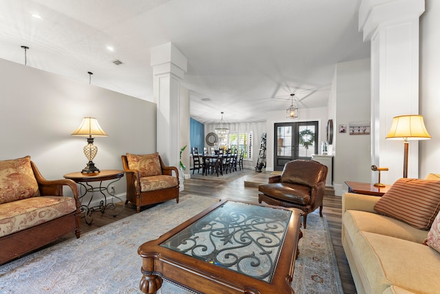 living room with french doors, ornate columns, hardwood / wood-style floors, and vaulted ceiling