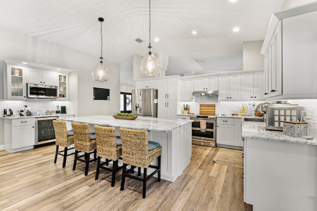 kitchen featuring white cabinets, wine cooler, decorative backsplash, a kitchen island, and stainless steel appliances