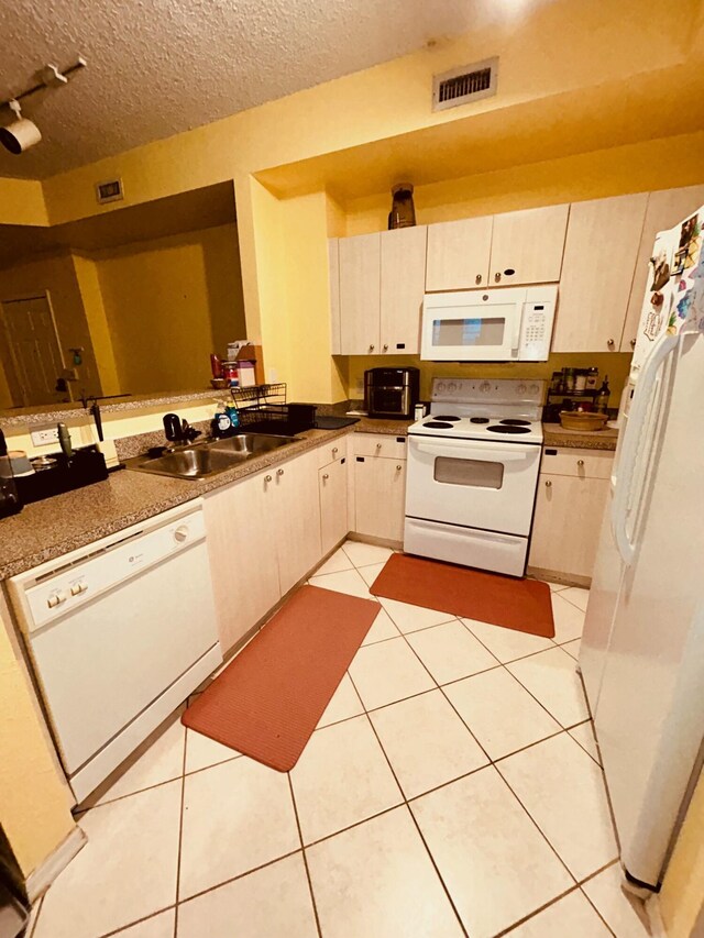 kitchen with sink, white appliances, rail lighting, a textured ceiling, and light tile patterned flooring