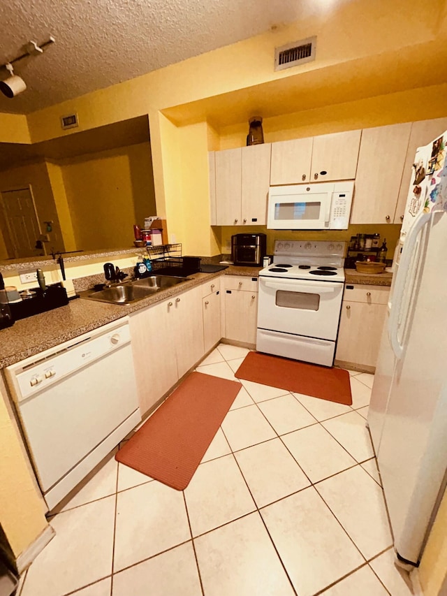 kitchen with white appliances, visible vents, light tile patterned flooring, a sink, and a textured ceiling