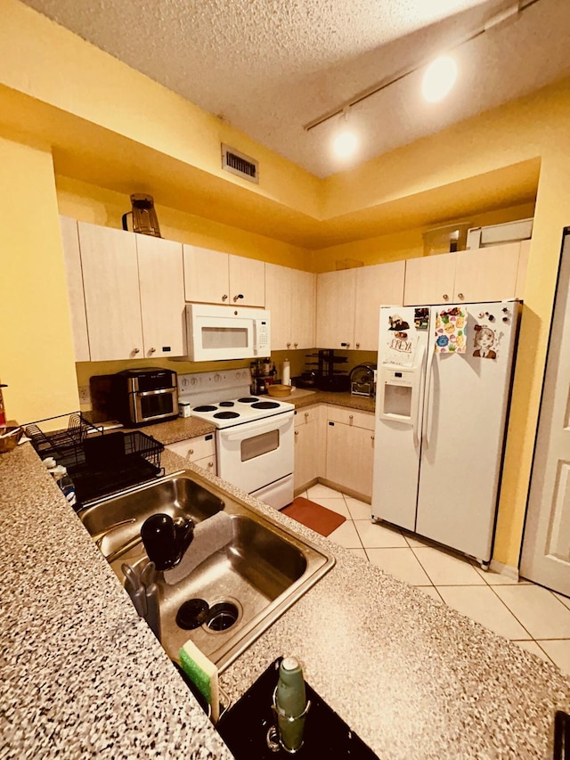 kitchen with visible vents, a sink, a textured ceiling, white appliances, and light tile patterned floors