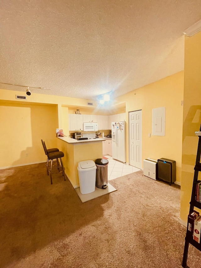 kitchen featuring white appliances, a kitchen breakfast bar, white cabinets, light colored carpet, and kitchen peninsula