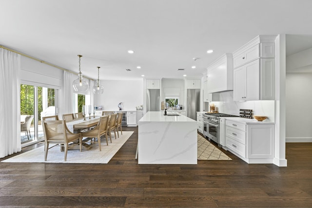 kitchen with hanging light fixtures, premium range hood, high end appliances, and dark wood-type flooring