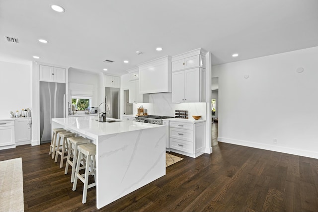 kitchen with custom exhaust hood, dark wood-type flooring, a large island with sink, and stainless steel appliances