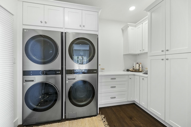 laundry room with cabinets, dark hardwood / wood-style floors, and stacked washer and clothes dryer