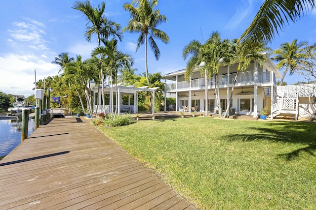 view of dock featuring a pergola, a balcony, a water view, and a lawn