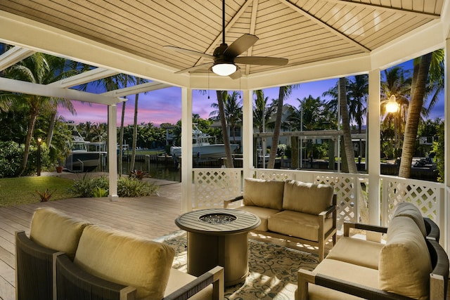 sunroom featuring ceiling fan, a water view, and wood ceiling