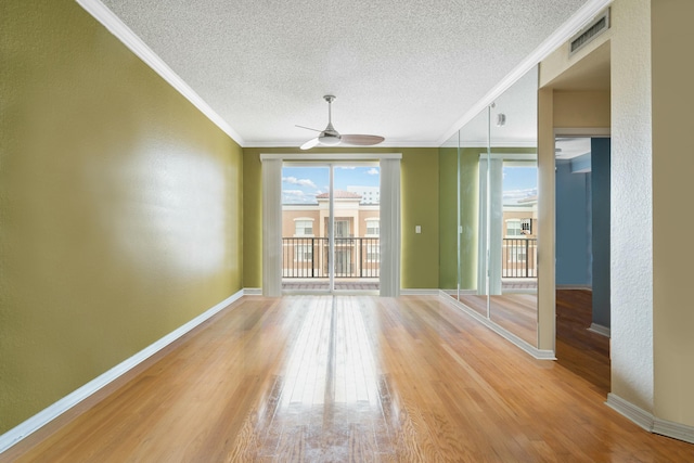 unfurnished room featuring ceiling fan, wood finished floors, visible vents, baseboards, and ornamental molding