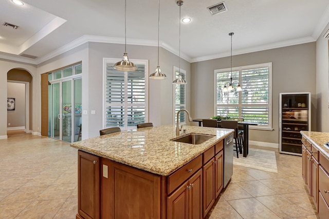 kitchen with dishwasher, sink, ornamental molding, light stone countertops, and an island with sink