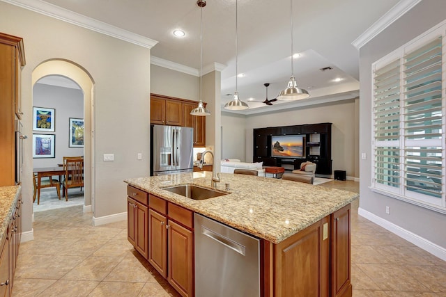 kitchen with light stone countertops, stainless steel appliances, sink, decorative light fixtures, and an island with sink