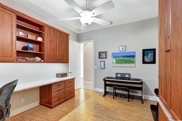 home office with ceiling fan, built in desk, and light hardwood / wood-style flooring