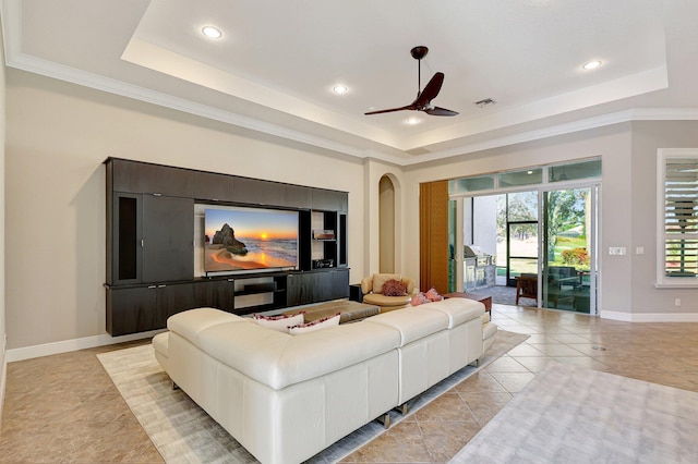 home theater room with ceiling fan, light tile patterned flooring, a raised ceiling, and crown molding