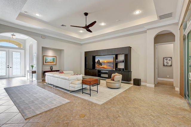 tiled living room with french doors, a tray ceiling, ceiling fan, and crown molding