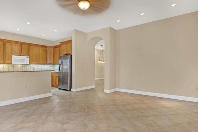 kitchen with light stone countertops, ceiling fan, stainless steel refrigerator with ice dispenser, decorative backsplash, and light tile patterned flooring