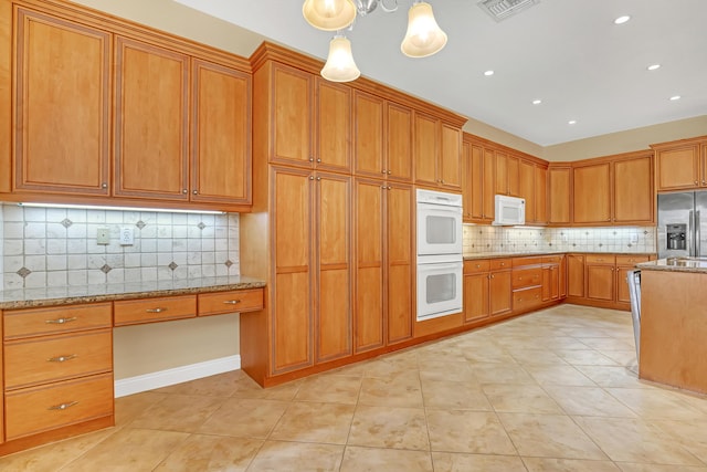 kitchen featuring light stone countertops, tasteful backsplash, white appliances, light tile patterned floors, and hanging light fixtures