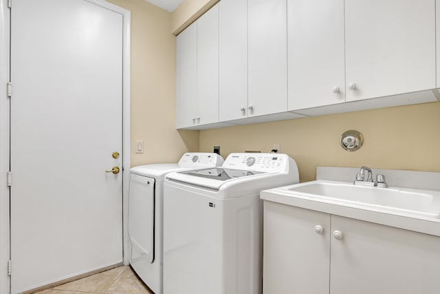 clothes washing area with washer and clothes dryer, cabinets, light tile patterned floors, and sink