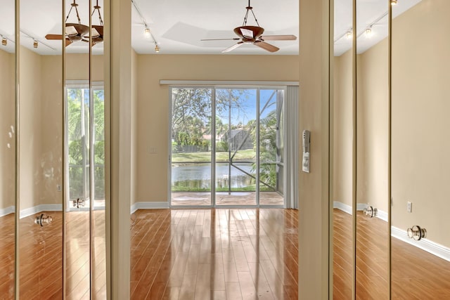 doorway to outside with ceiling fan, a water view, and hardwood / wood-style flooring