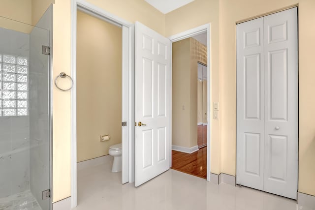 bathroom with a shower with door, tile patterned flooring, and toilet