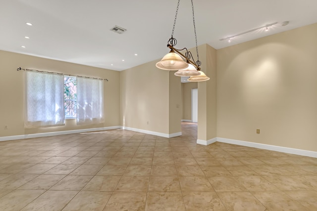 tiled spare room featuring track lighting