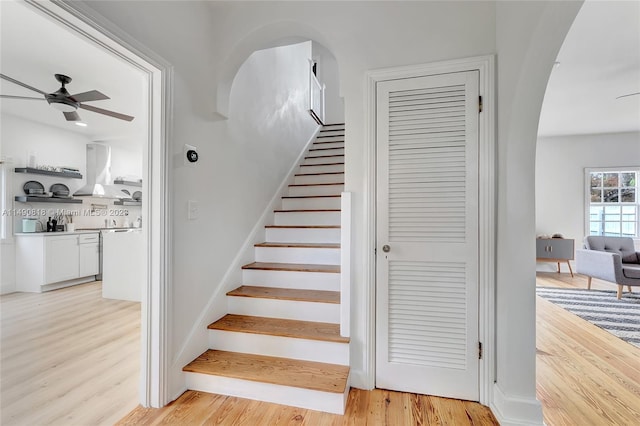 stairway with ceiling fan and wood-type flooring