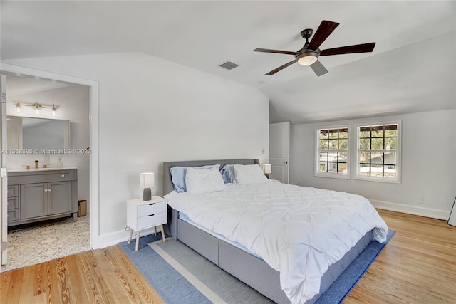 bedroom featuring ceiling fan, ensuite bath, lofted ceiling, and light hardwood / wood-style flooring