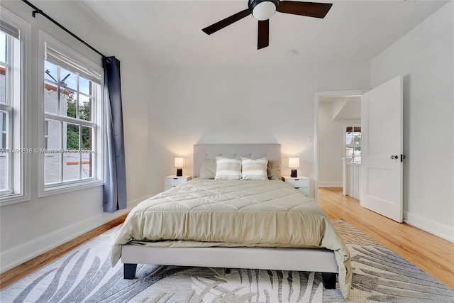 bedroom with multiple windows, ceiling fan, and light hardwood / wood-style floors