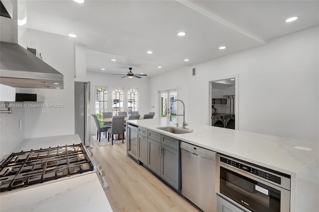 kitchen featuring island exhaust hood, appliances with stainless steel finishes, ceiling fan, sink, and washing machine and dryer