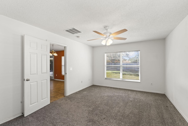 spare room with dark colored carpet, ceiling fan with notable chandelier, and a textured ceiling