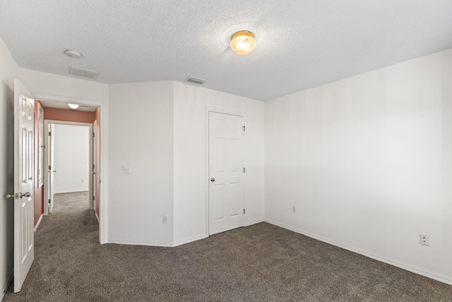 unfurnished bedroom featuring dark carpet, a textured ceiling, and a closet