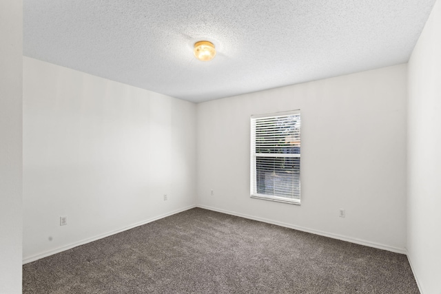 empty room with dark colored carpet and a textured ceiling