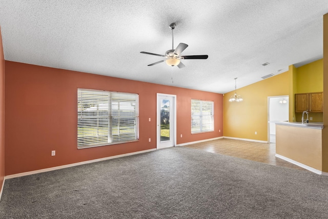 unfurnished living room featuring ceiling fan with notable chandelier, sink, vaulted ceiling, a textured ceiling, and carpet floors