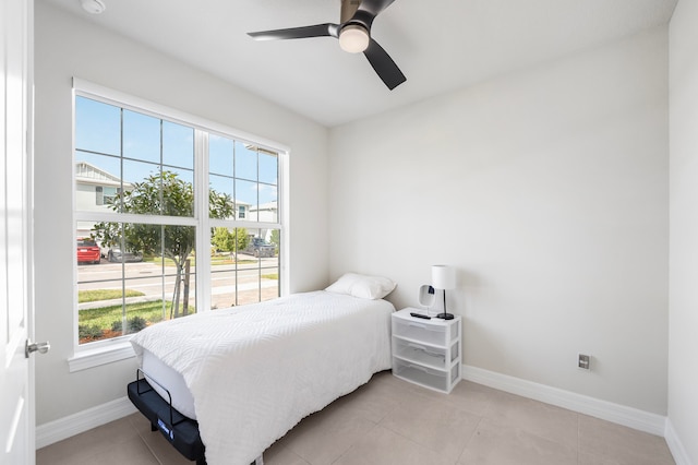 tiled bedroom featuring ceiling fan and multiple windows