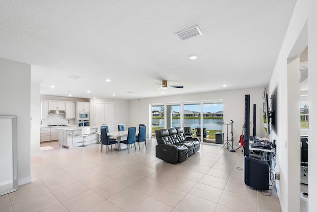 tiled living room with ceiling fan and a textured ceiling