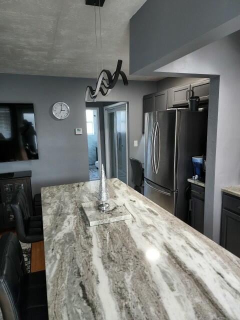 kitchen featuring light stone counters, gray cabinetry, and stainless steel fridge