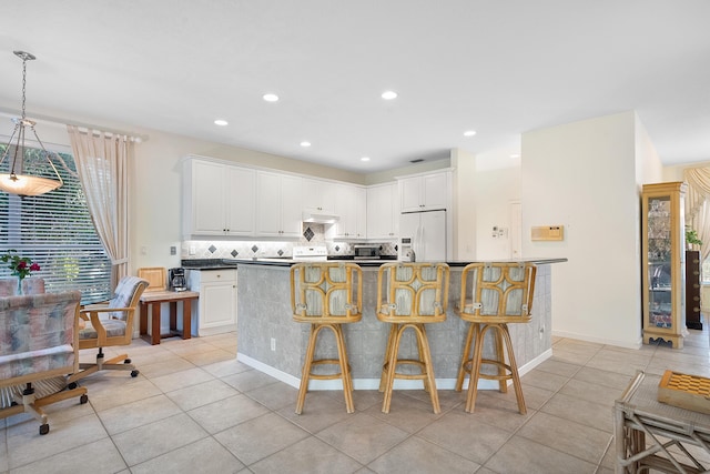 kitchen with white cabinetry, white fridge with ice dispenser, a breakfast bar area, and hanging light fixtures