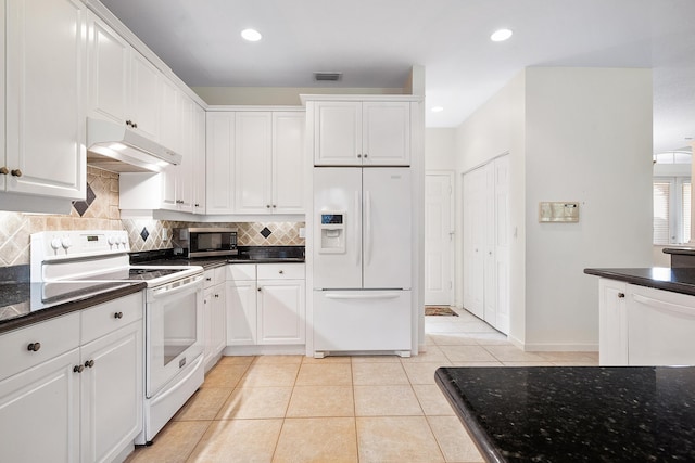 kitchen with decorative backsplash, dark stone counters, white appliances, light tile patterned floors, and white cabinetry