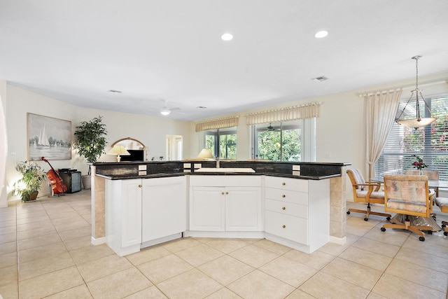 kitchen featuring white dishwasher, white cabinets, an island with sink, and hanging light fixtures